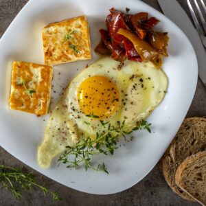Fried egg with fried cheese, butter and some pickles