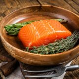 Healthy food - fresh salmon fillet steak with herbs. Wooden background. Top view