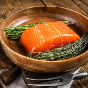 Healthy food - fresh salmon fillet steak with herbs. Wooden background. Top view