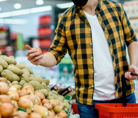 Young handsome man in a supermarket wearing protective mask while grocery shopping